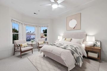 San Francisco apartment for rent - A bedroom with a large bed, a chair, and a window overlooking a cityscape.
