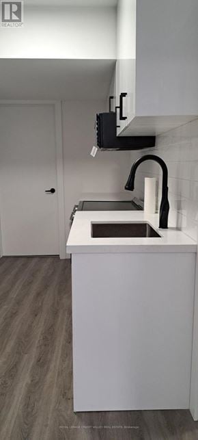 Innisfil (Alcona) house for rent - A white kitchen with a sink and a black microwave.