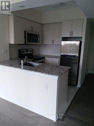 Toronto (Clanton Park) condo for rent - A kitchen with white cabinets and a granite countertop.
