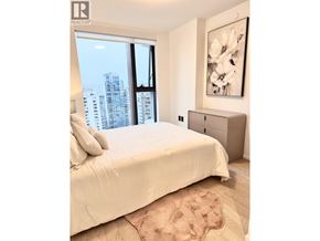 Vancouver apartment for rent - A bedroom with a large bed and a city view through the window.