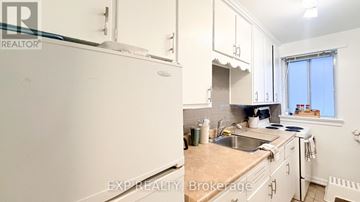 Ottawa multi-family for rent - A kitchen with white cabinets and a white refrigerator.
