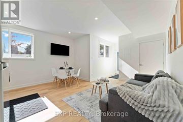 Ottawa multi-family for rent - A living room with a grey couch and a white dining table.