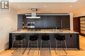 Toronto (Bay Street Corridor) condo for rent - A modern kitchen with a marble countertop and bar stools.