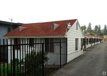 Los Angeles apartment for rent - A white house with a red roof and a black fence.