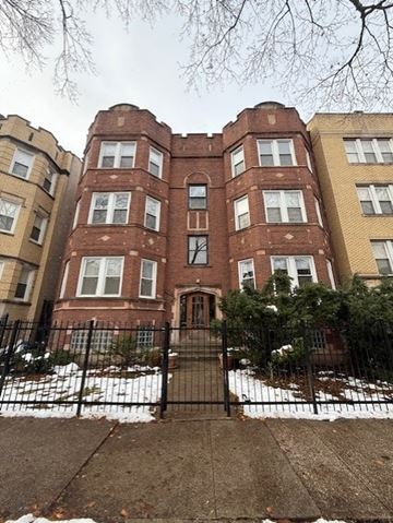 Chicago apartment for rent - A large red brick building with a black gate in front.