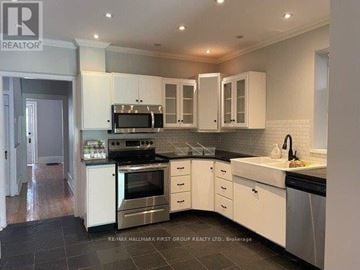 Cobourg house for rent - A kitchen with white cabinets and black countertops.