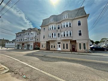 Woonsocket apartment for rent - A large, two-story building with a flat roof and a balcony on the second floor.