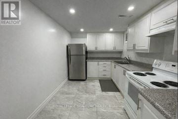 Toronto (Rouge) house for rent - A kitchen with white cabinets and a black refrigerator.
