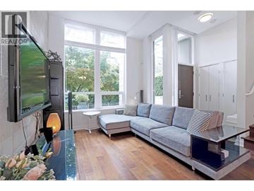 Vancouver townhouse for rent - A modern living room with a grey sofa and a television on the wall.