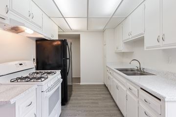 Fullerton apartment for rent - A kitchen with white cabinets and a black refrigerator.