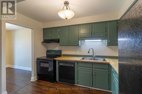 Thorold (Confederation Heights) townhouse for rent - A kitchen with a black refrigerator and white cabinets.