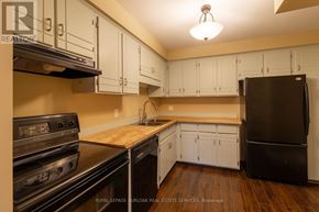 Thorold (Confederation Heights) townhouse for rent - A kitchen with white cabinets and a black refrigerator.
