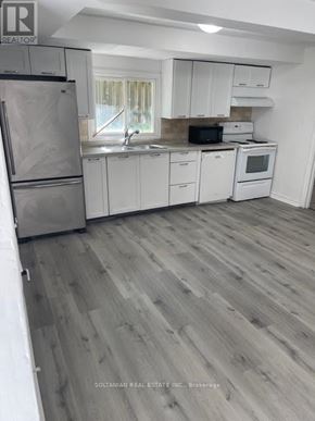 Georgina (Keswick South) duplex for rent - A kitchen with white cabinets and a wooden floor.