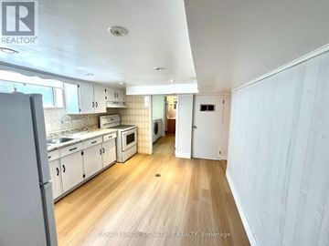 Toronto (Stonegate-Queensway) house for rent - A kitchen with white cabinets and a wooden floor.