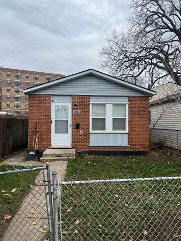 Chicago apartment for rent - A small house with a white door and windows is surrounded by a chain link fence.