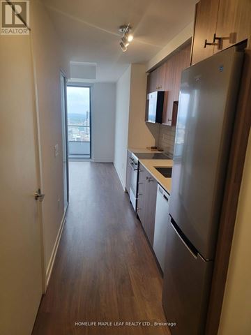 Kitchener condo for rent - A kitchen with a refrigerator, cabinets and a window.