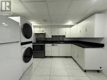 Ajax (Central West) house for rent - A white kitchen with a black counter top and a washing machine.