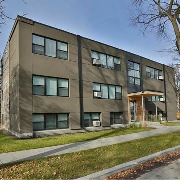 Winnipeg apartment for rent - A modern building with a brown facade and a tree in front.