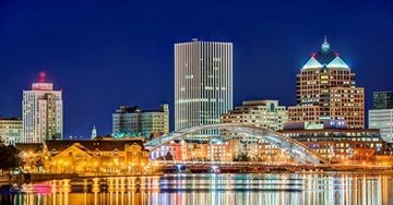 Rochester apartment for rent - A cityscape at night with a river in the foreground.