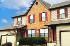 Reynoldsburg triplex for rent - a yellow brick house with red shutters and a blue sky