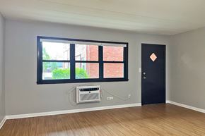 Forest Park apartment for rent - A room with a black door and a window with a view of a brick building outside.