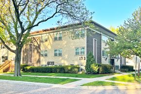 Forest Park apartment for rent - A building with the number 133 on it is surrounded by trees and bushes.