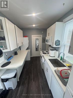 London North (North N) triplex for rent - A kitchen with white cabinets and a wooden floor.