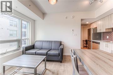 Waterloo condo for rent - A modern living room with a grey sofa and a wooden dining table.