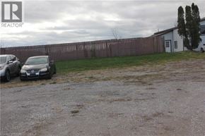 Cayuga house for rent - Two cars parked in front of a white house with a brown fence.