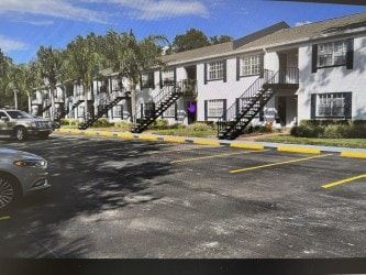 Tampa apartment for rent - A parking lot with a car and a building with a staircase.