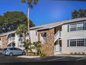Tampa apartment for rent - A blue car is parked in front of a two-story building with a brick facade and a balcony.