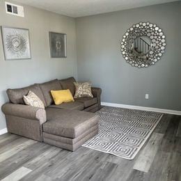 Atlanta apartment for rent - A grey couch with a yellow pillow is in the middle of a room with a grey floor and a grey wall.