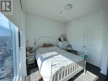 Toronto (Henry Farm) condo for rent - A bedroom with a large bed and a view of the city.