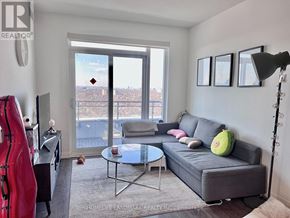 Toronto (Henry Farm) condo for rent - A living room with a grey couch, a glass table, a red sculpture, and a view of the city through the window.