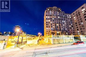 Hamilton (Corktown) condo for rent - A nighttime city street with a large building in the background and a car driving on the road.