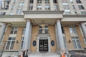 Hamilton (Corktown) condo for rent - A large building with a black door and two circular windows flanked by two large columns.