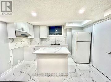 Toronto (Malvern) townhouse for rent - A white kitchen with a marble floor and a fridge.