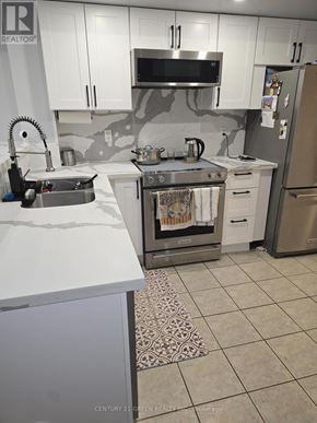Toronto (York University Heights) townhouse for rent - A kitchen with a refrigerator, sink, and stove.