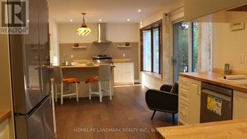 Mississauga (Sheridan) house for rent - A modern kitchen with a refrigerator, sink, and dining table.