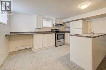 Kitchener house for rent - A kitchen with white cabinets and a granite countertop.