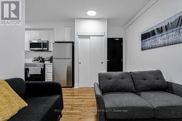 Hamilton (Landsdale) other for rent - A living room with a grey couch and a black fridge.