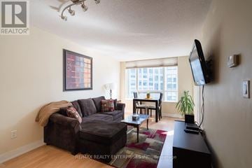 Toronto (Waterfront Communities) condo for rent - A living room with a brown couch and a flat screen TV mounted on the wall.