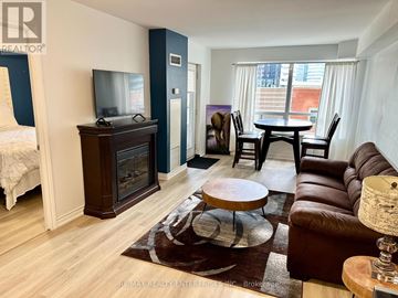 Toronto (Waterfront Communities) condo for rent - A living room with a brown leather couch and a wooden coffee table.