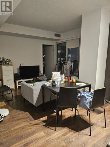 Toronto (Waterfront Communities) condo for rent - A living room with a grey couch, a black chair, and a dining table with chairs.