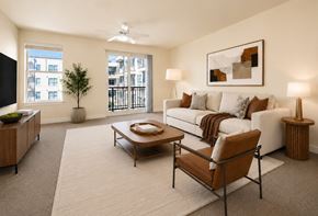 New Orleans apartment for rent - Sun-lit apartment living room with balcony access and carpet, decorated with contemporary furniture and decor in browns and neutrals.