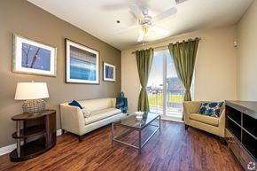 New Orleans apartment for rent - A living room with a white couch, a glass coffee table, and a ceiling fan.
