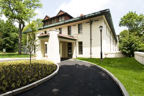 Staten Island apartment for rent - a large white house with a driveway and lawn and trees