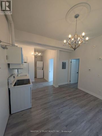 Uxbridge condo for rent - A well-lit, spacious room with a kitchenette and a chandelier.