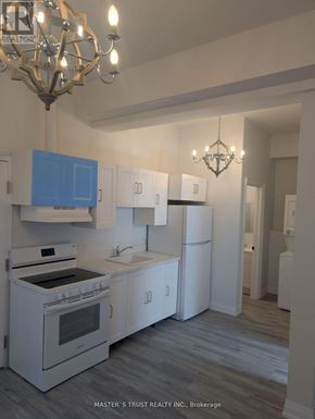 Uxbridge condo for rent - A kitchen with white appliances and blue cabinets.