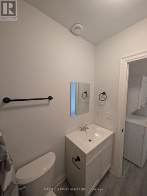 Uxbridge condo for rent - A white bathroom with a toilet, sink, and mirror.